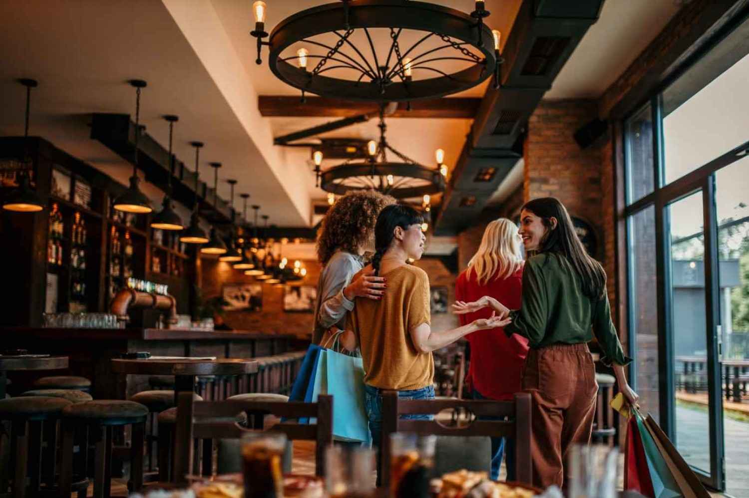 Grupo de mulheres entrando em restaurante aconchegante e sofisticado em Belo Horizonte, com clima acolhedor e iluminação intimista.