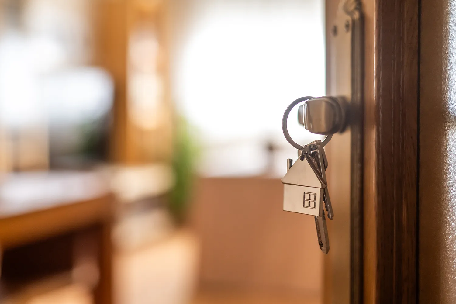 Chave com chaveiro em formato de casa na porta de um apartamento novo