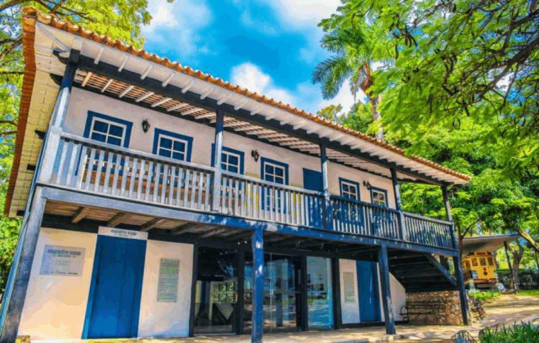Museu Histórico Abílio Barreto, casarão colonial preservado, com fachada branca e detalhes em azul, rodeado por árvores, representando a memória e a história de Belo Horizonte.