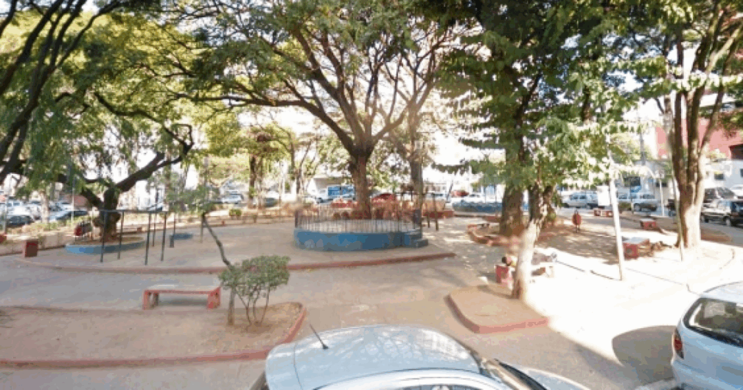Praça Leonardo Gutierrez, com árvores frondosas, bancos e um espaço de lazer tranquilo, um refúgio de sombra e convivência no coração do bairro.