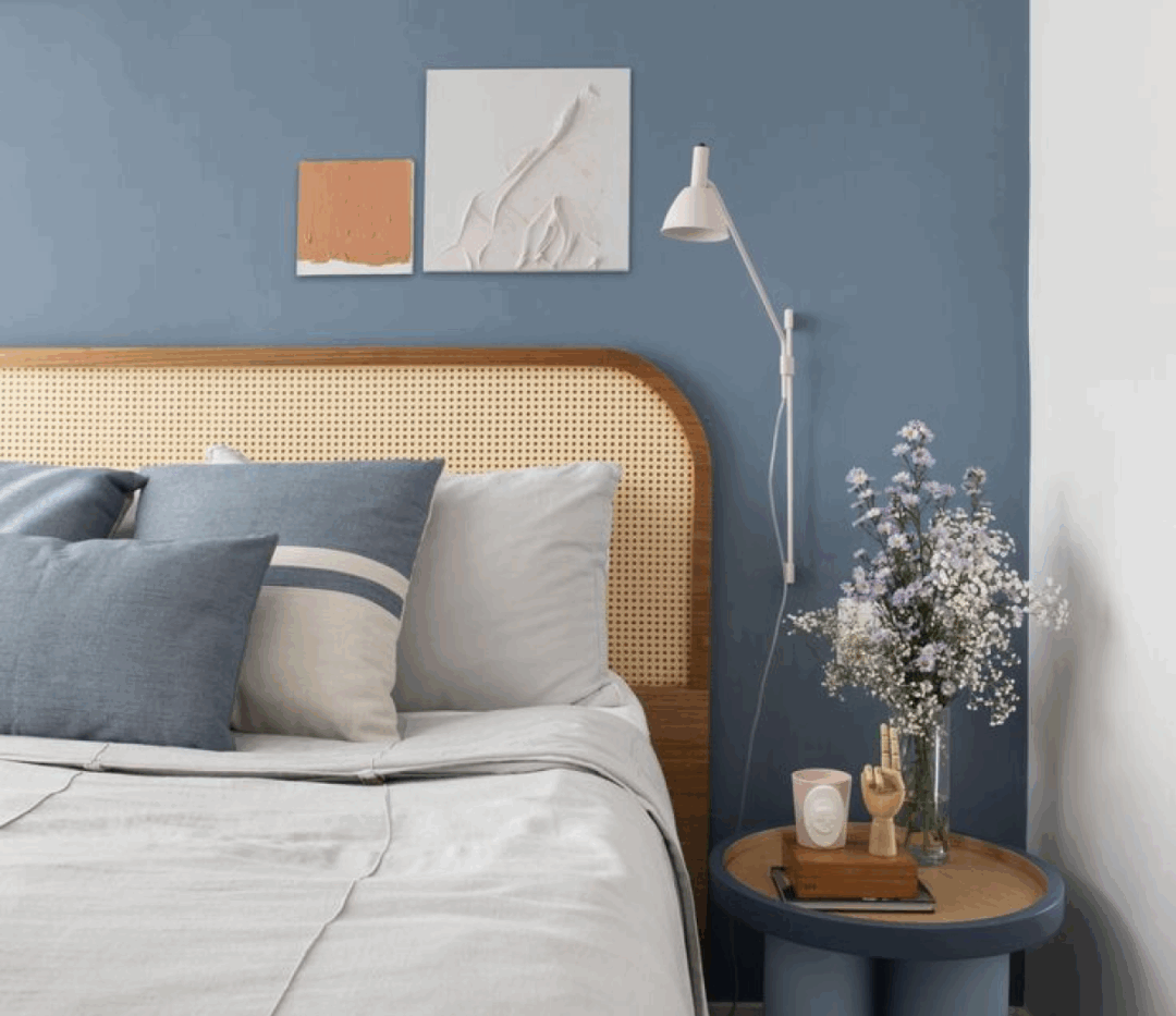 Quarto de solteiro com decoração minimalista em tons claros, parede azul suave e cortina branca translúcida.