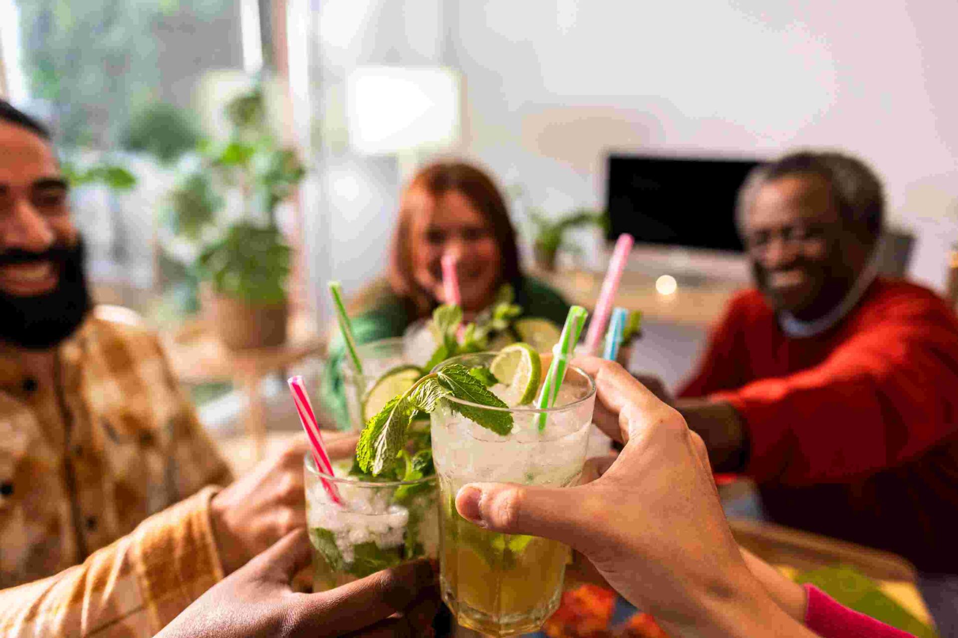 Grupo de amigos brindando com drinks em copos com hortelã e limão.