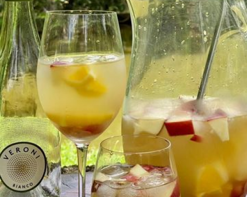 Taça de clericot com frutas frescas, acompanhada por jarra ao fundo.