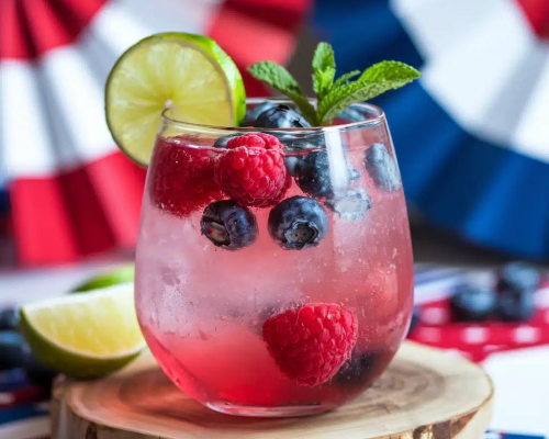 Copo com frutas vermelhas frescas, rodela de limão e gelo sobre base espumante.