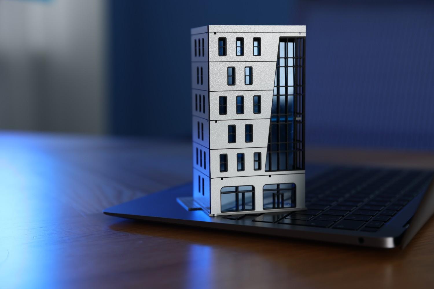 Modelo de prédio de apartamentos e laptop na mesa
